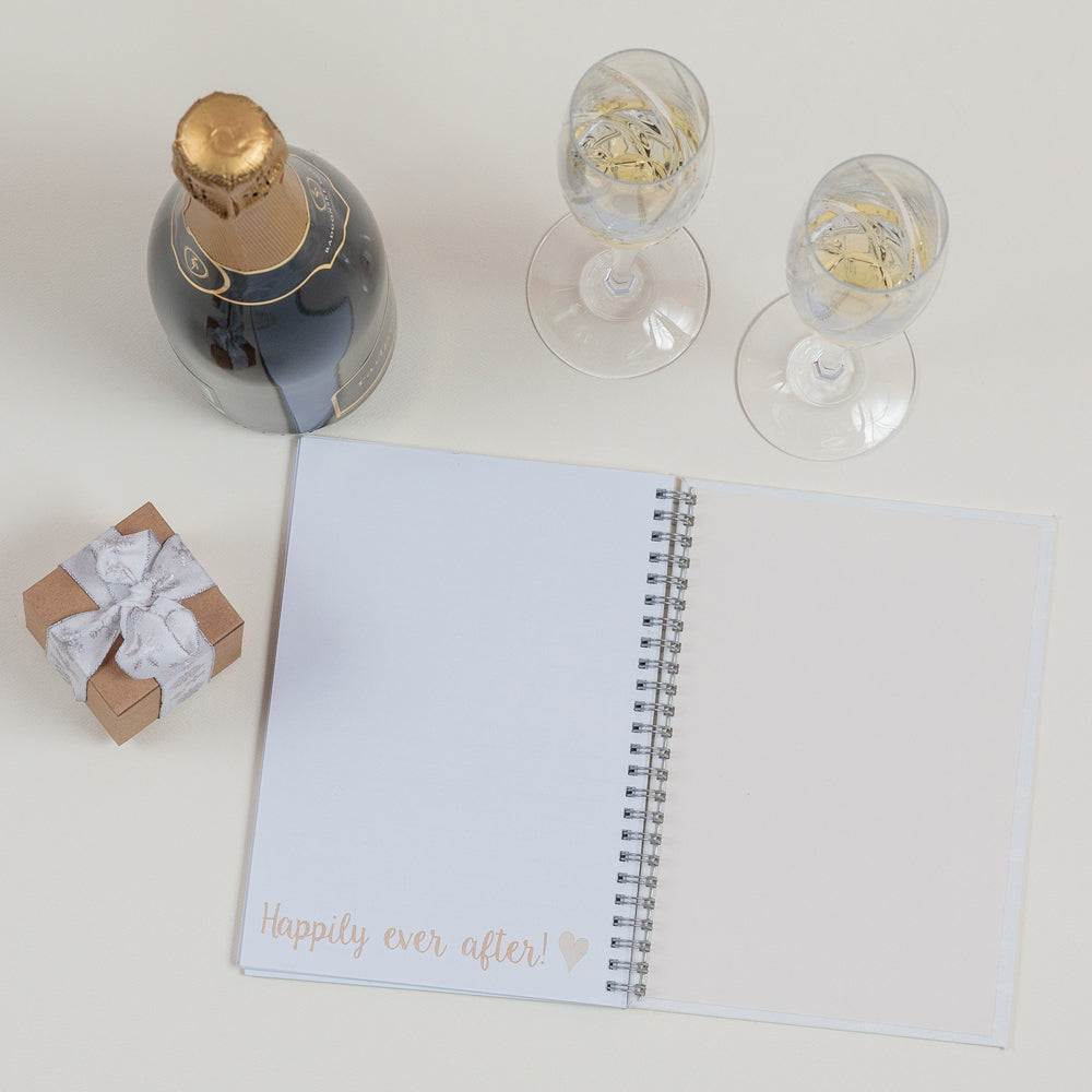 the inside of a wedding planner with a small gift, bottle and two glasses of champagne aside