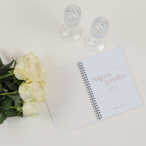 first page of a wedding planner with two glasses of champagne and white roses beside